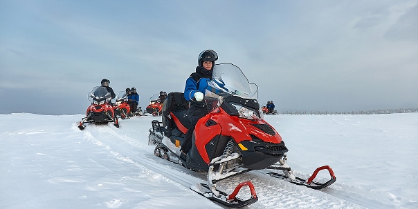 Photo of a group of people on red snowmobiles