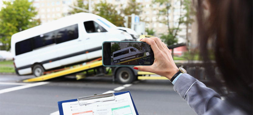 Woman takes a picture of a commercial van as it gets towed away