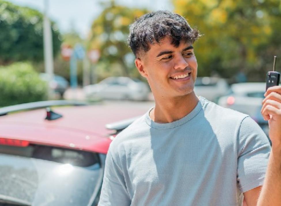 Foto de un hombre joven con seguro de auto sosteniendo la llave de su carro