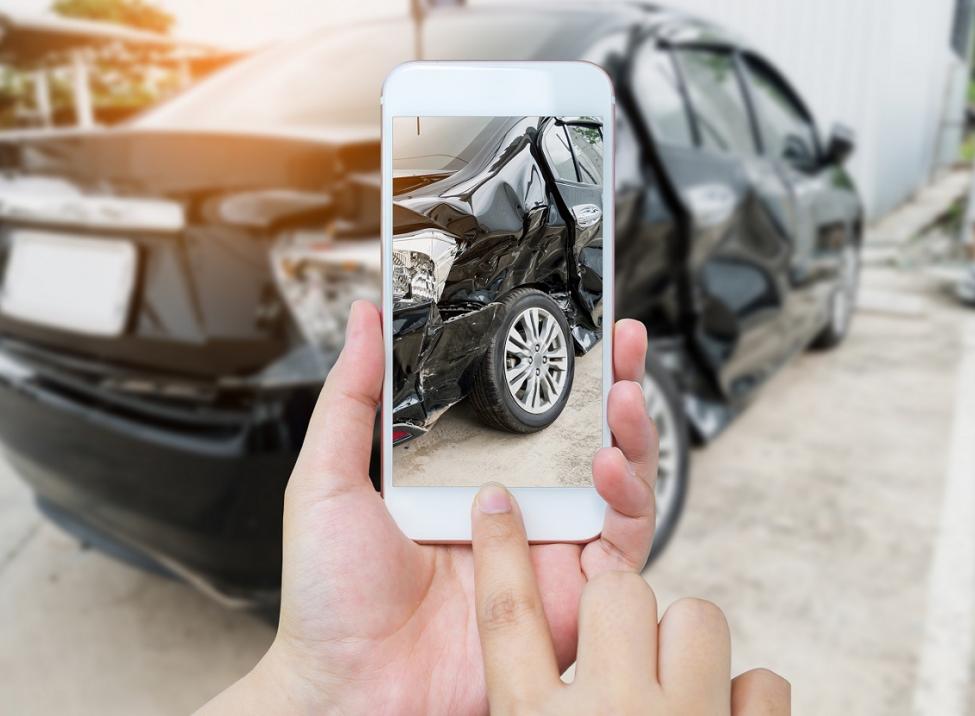 Alguien tomando una fotografía de un auto dañado