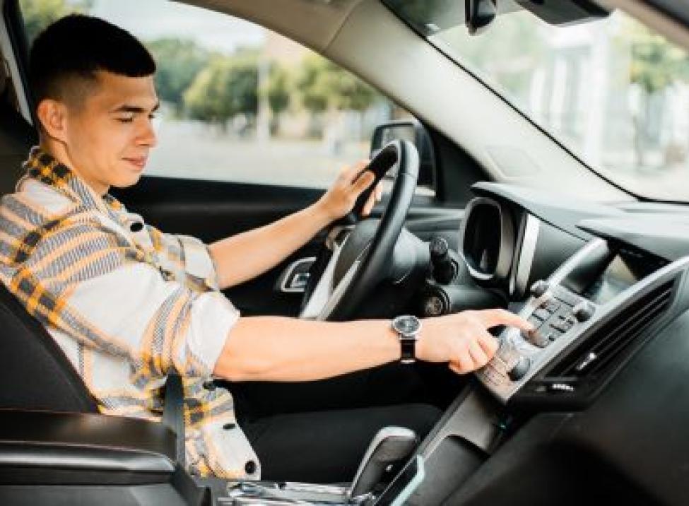 Man driving and looking at the audio controls on the car instead of the road.